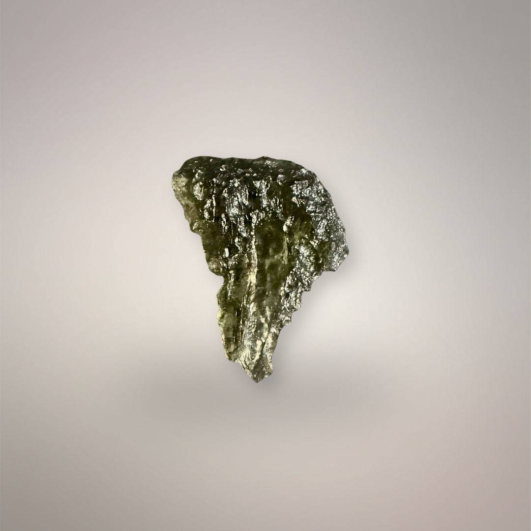 Reverse view of Czech Republic Moldavite showing its tapered tear outline, reflective olive surface, vertical grooves, and elongated gas tube.