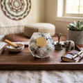 Rainbow Moonstone orgonite dodecahedron with golden Flower of Life symbol displayed on a wooden tray beside incense, journal, plant, and ritual décor