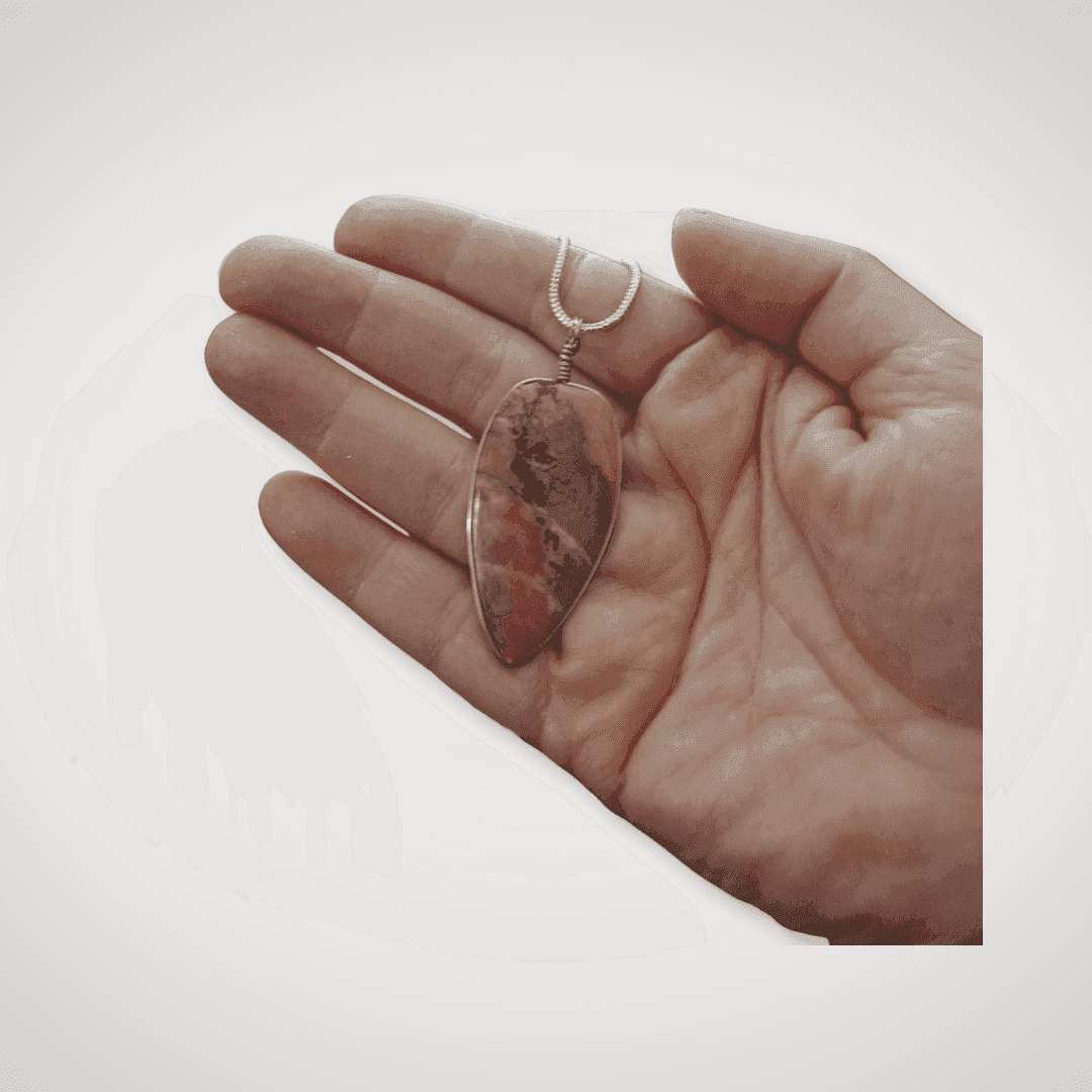 Close-up of Rhodonite pendant in hand