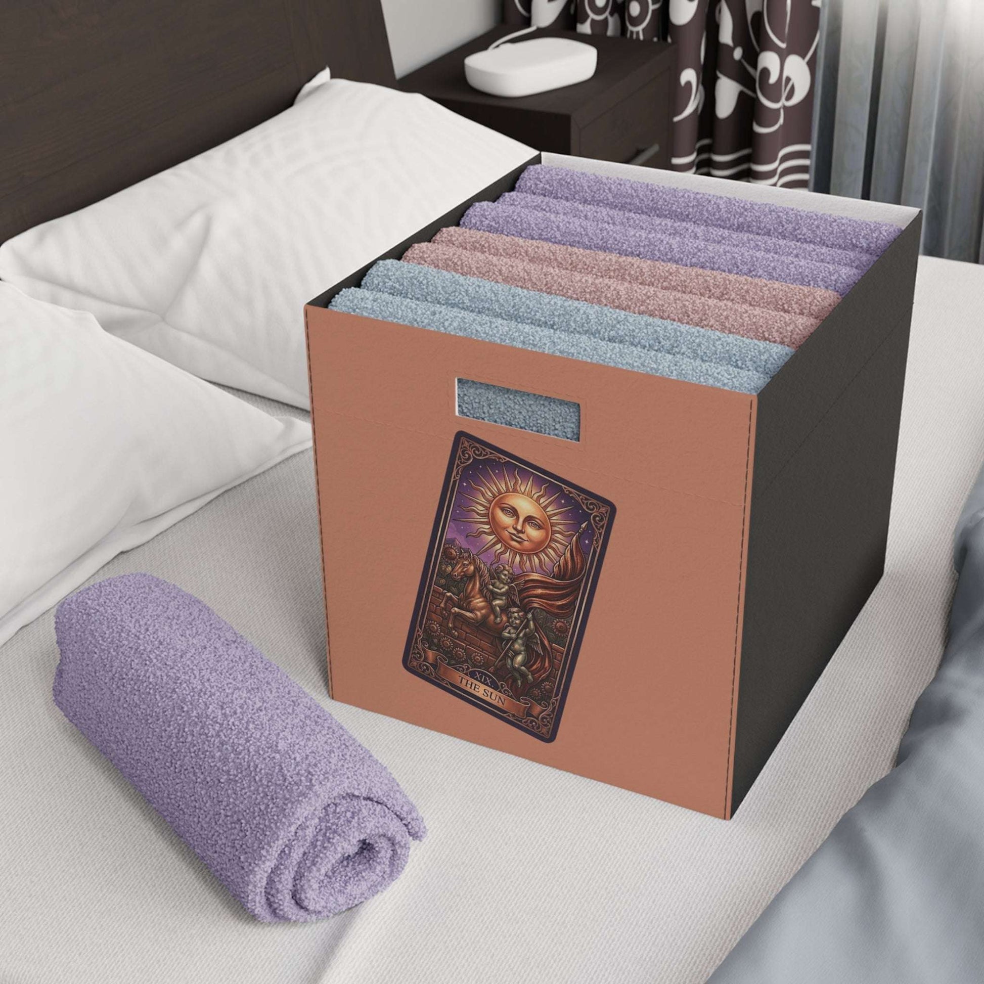 Folded towels in a decorative storage box on a bed