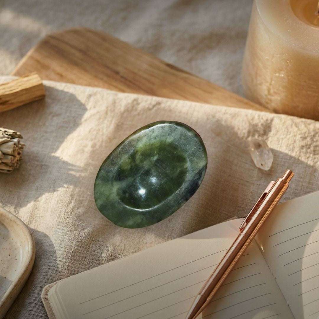 Green nephrite palm stone on wooden surface for grounding and protection