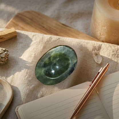 Green nephrite palm stone on wooden surface for grounding and protection