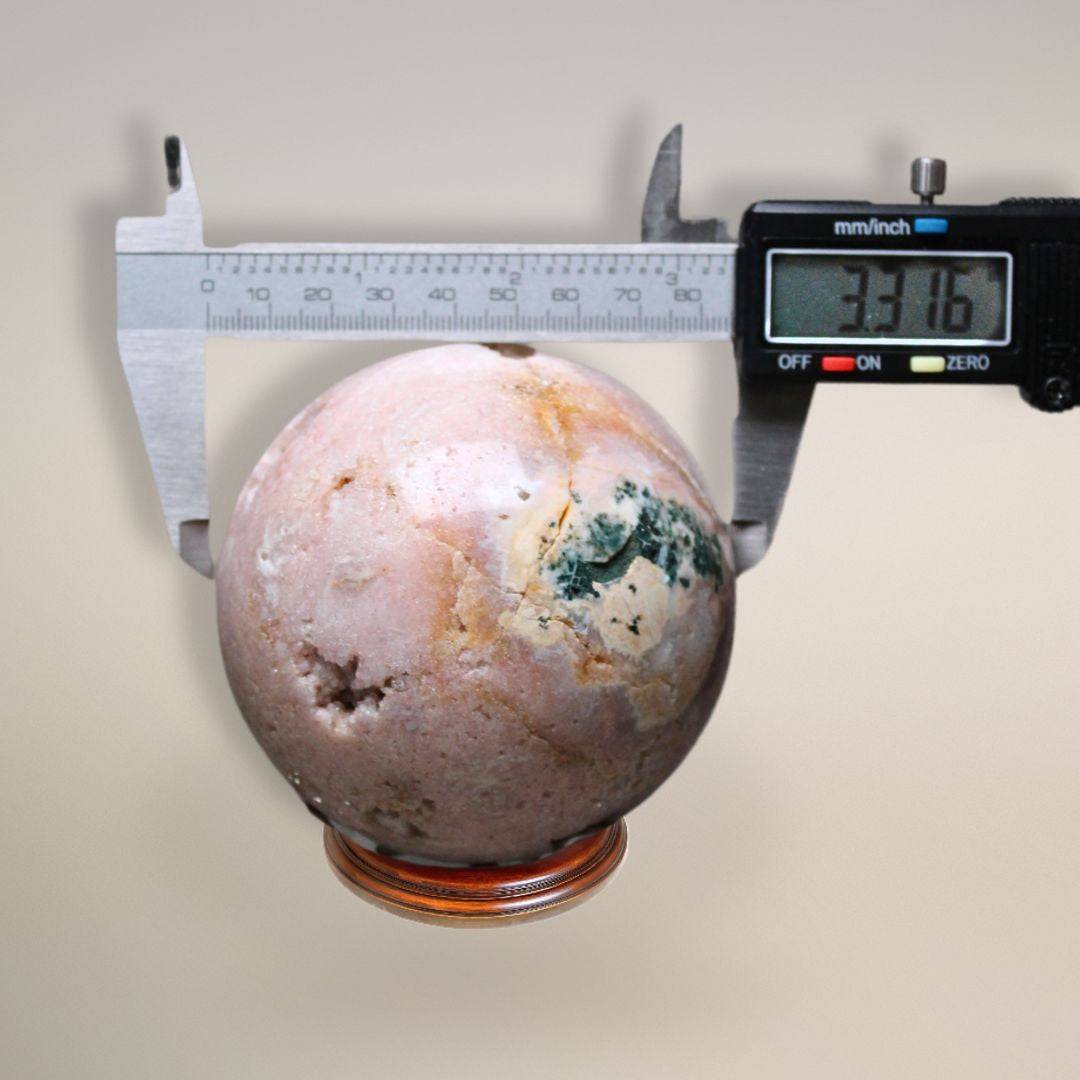 Pink amethyst sphere being measured with digital calipers reading 3.316 inches in diameter.