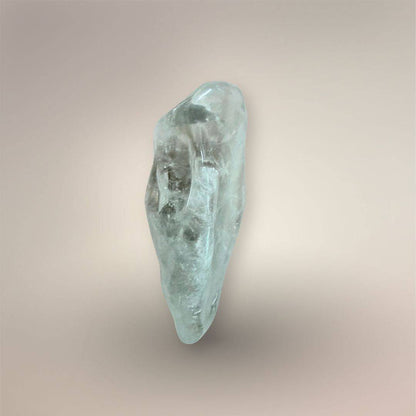 Pale green Prasiolite freeform palm stone shown upright against a warm neutral background, with translucent quartz and visible internal veils.