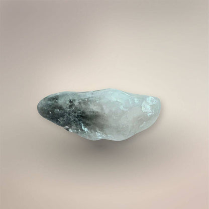 Side view of a pale green Prasiolite freeform palm stone showing its asymmetrical tumbled profile and cloudy internal inclusions.