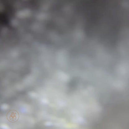 Close-up video of an 80 mm Clear Quartz sphere from Madagascar on a wooden display base, revealing natural internal veils, featherlike fractures, and subtle rainbow light refractions as the camera moves closer.
