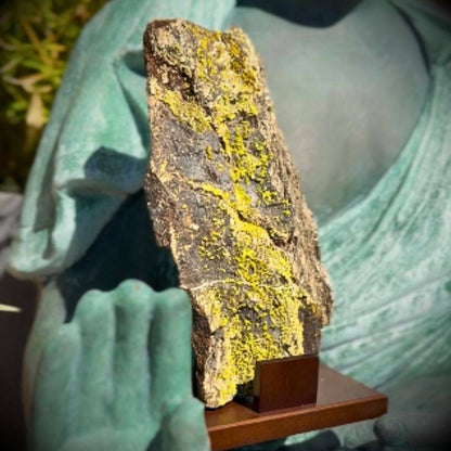 Lifestyle in-hand scale view showing the pyromorphite piece resting against the hand of a bronze statue.