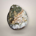 Brazilian quartz geode with chlorite-included green quartz and cream calcite crystals, front view showing open cavity structure