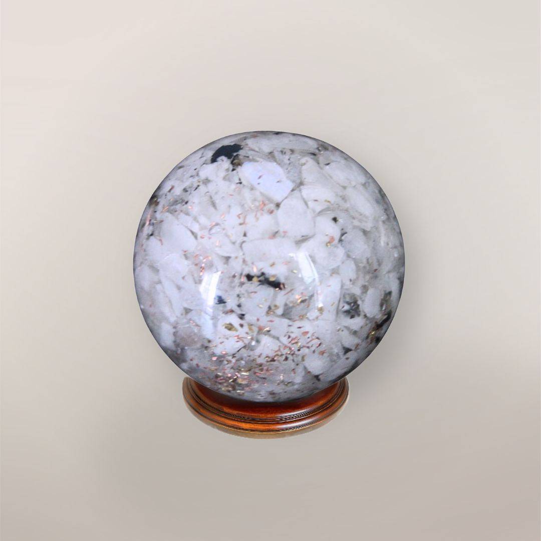 Back view of handmade Rainbow Moonstone orgonite sphere showing pale stone chips, copper flakes, and resin texture