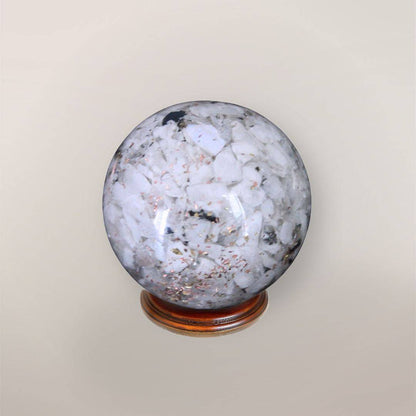Back view of handmade Rainbow Moonstone orgonite sphere showing pale stone chips, copper flakes, and resin texture