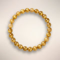 Golden Rutile Quartz 6mm beaded bracelet displayed on a clear stand, for clarity and intuitive flow.