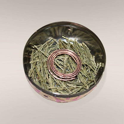 Inside the Safe Travels Ritual Box showing loose Mt. Shasta cedar and a hand-formed copper spiral at the base of the box