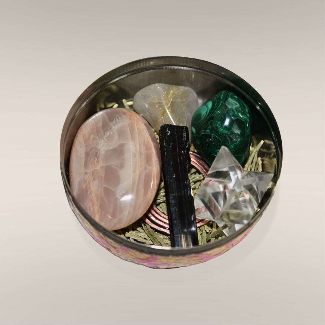 Close-up of the Safe Travels Ritual Box interior with Peach Moonstone, Black Tourmaline schorl barrel, Malachite, Rutilated Quartz, Clear Quartz Merkabah, cedar, and copper spiral