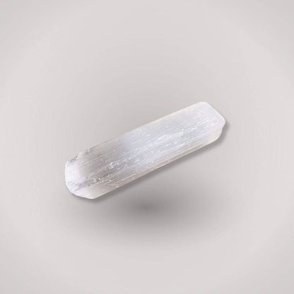 Unpolished selenite (satin spar) stick showing a bright, natural fibrous structure and cleanly cut edges against a neutral background.