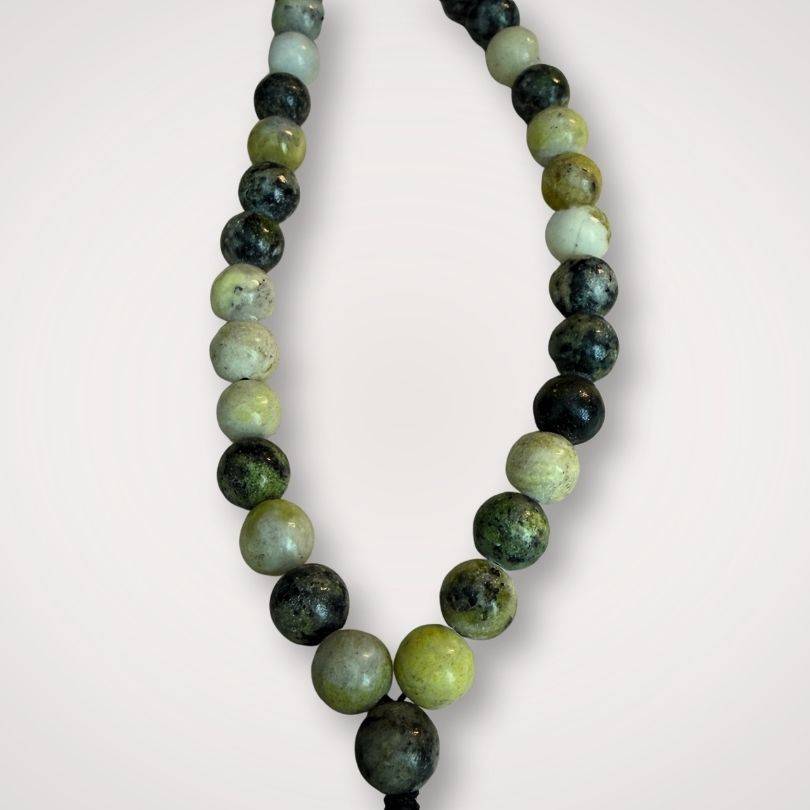 Close-up of Serpentine Mala beads showing natural green and black patterns; 8mm polished stones ideal for spiritual grounding and renewal meditation.