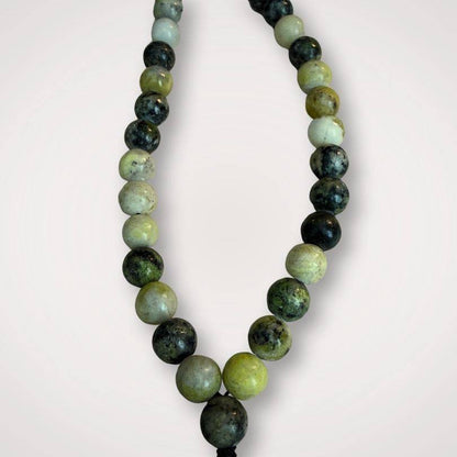 Close-up of Serpentine Mala beads showing natural green and black patterns; 8mm polished stones ideal for spiritual grounding and renewal meditation.