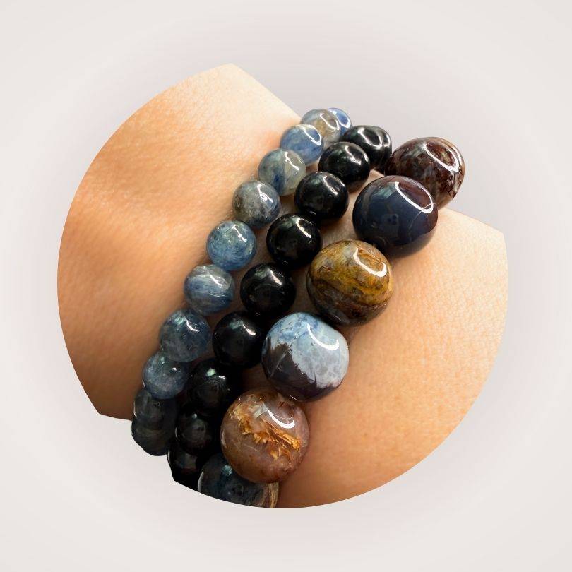 Shungite Beaded Bracelet 8mm worn with other gemstone bracelets, highlighting its minimalist black beads and root chakra support benefits.
