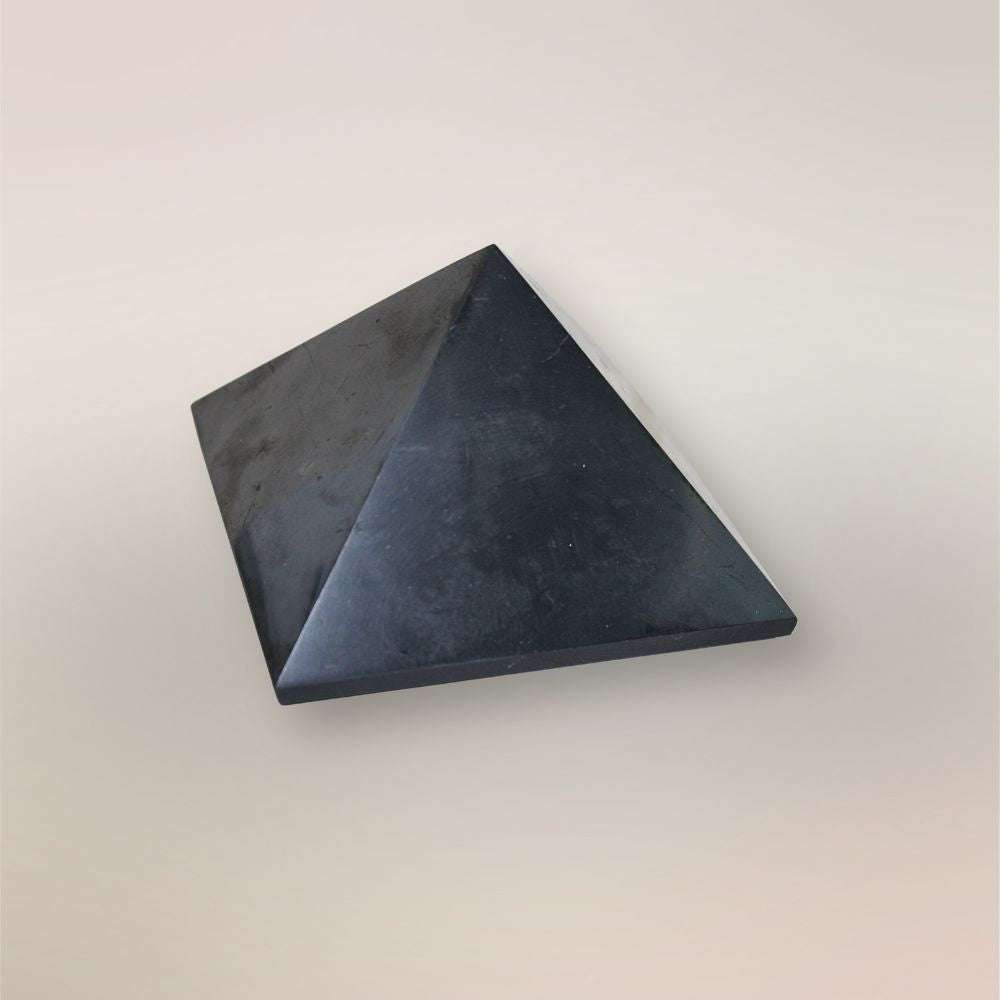 Polished Shungite pyramid from Russia angled view on a light neutral background