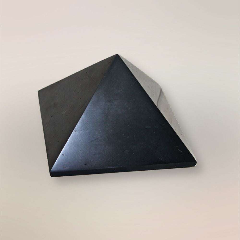 Front view of polished Shungite pyramid from Russia on a light neutral background