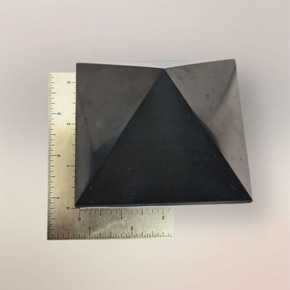 Shungite pyramid from Russia shown with ruler for scale on a light background