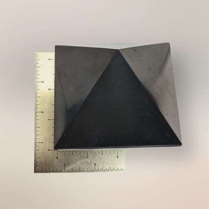 Shungite pyramid from Russia shown with ruler for scale on a light background
