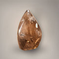 Brazilian Smoky Quartz Flame displayed on a wooden table beside incense and decorative books in a warm, neutral interior.
