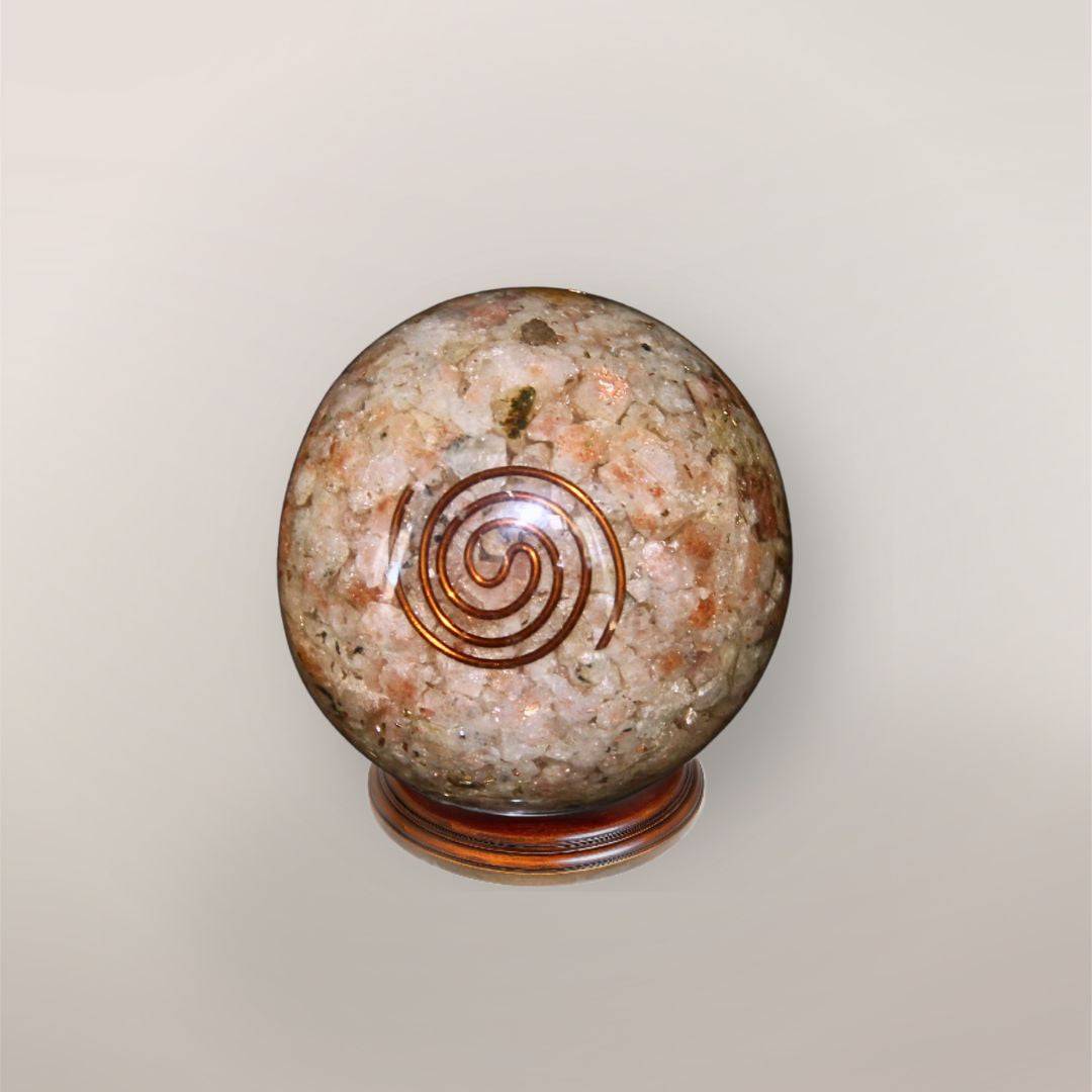 Sunstone orgonite sphere with Indian Sunstone chips, copper spiral, copper flakes, and wood display stand