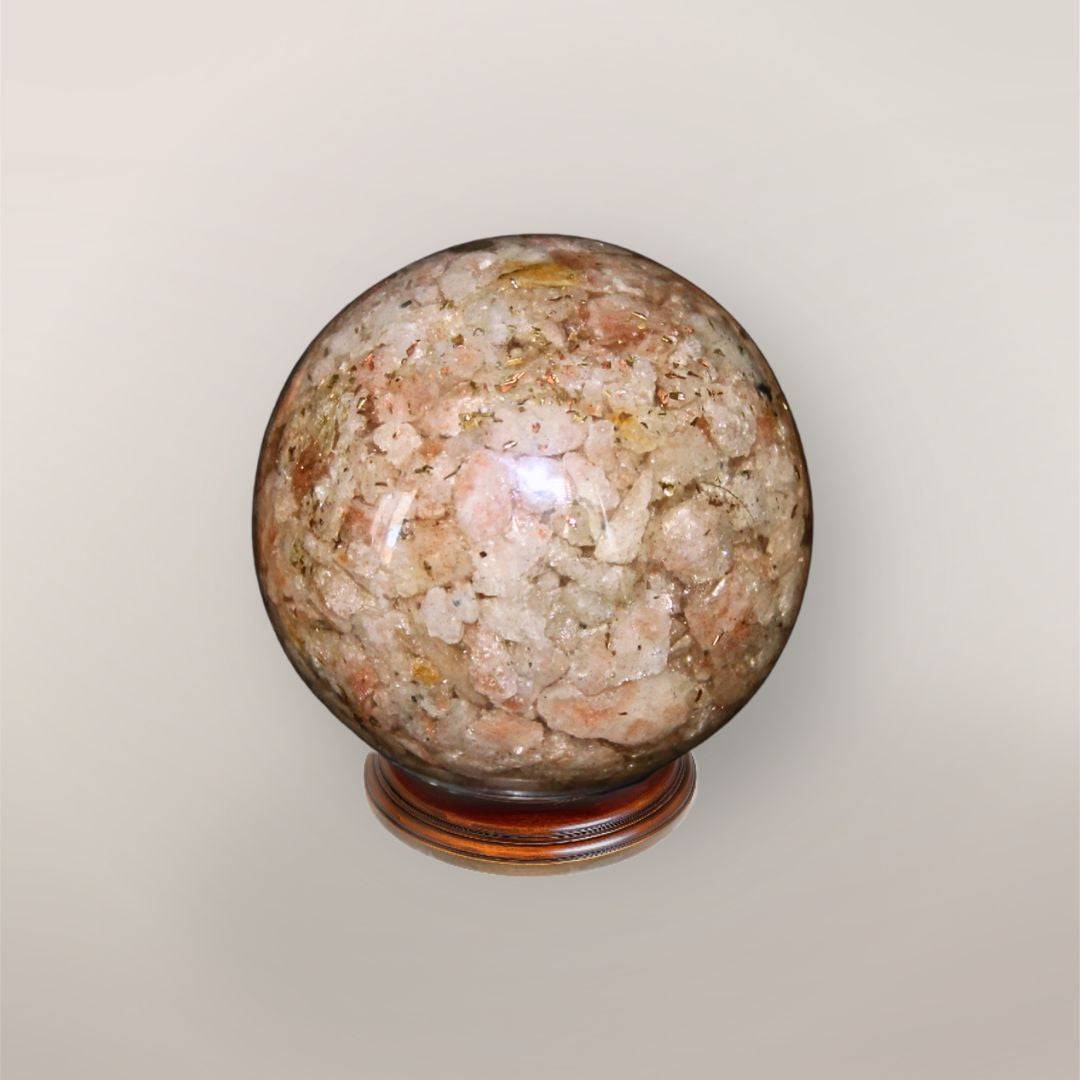 Back view of handmade Sunstone orgonite sphere showing peach-toned stone chips, copper flakes, and resin texture