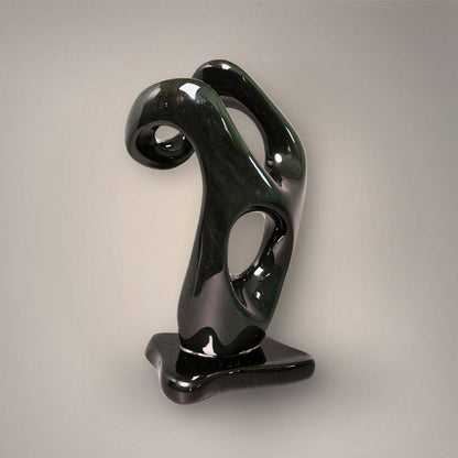 Angled view of polished black and green Velvet Rainbow Obsidian sculpture showing its curved upper section and sculpted openings.