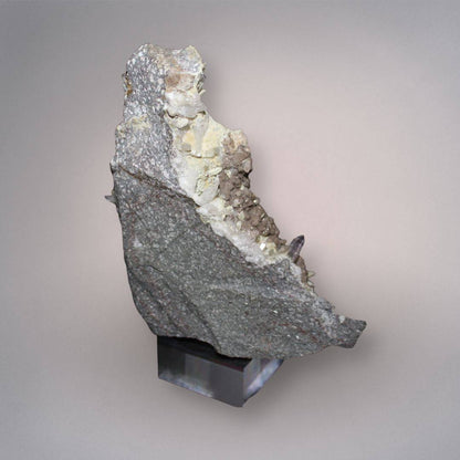 Back view of Mexico Veracruz Amethyst cluster showing the gray volcanic matrix, pale mineral growth, and exposed crystal edges on the included stand.