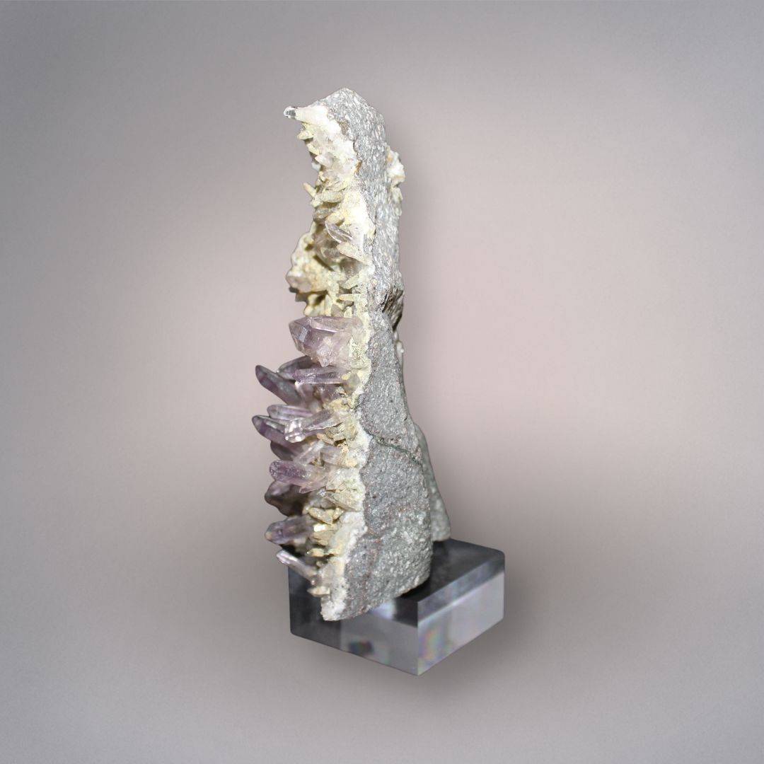 Side profile of Mexico Veracruz Amethyst showing slender projecting quartz crystals along the edge of the volcanic matrix on the included stand.