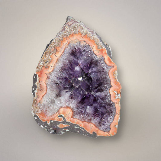 Polished Waldhambach agate from Germany showing iron-rich rose-orange banding around a deep amethyst-filled center.