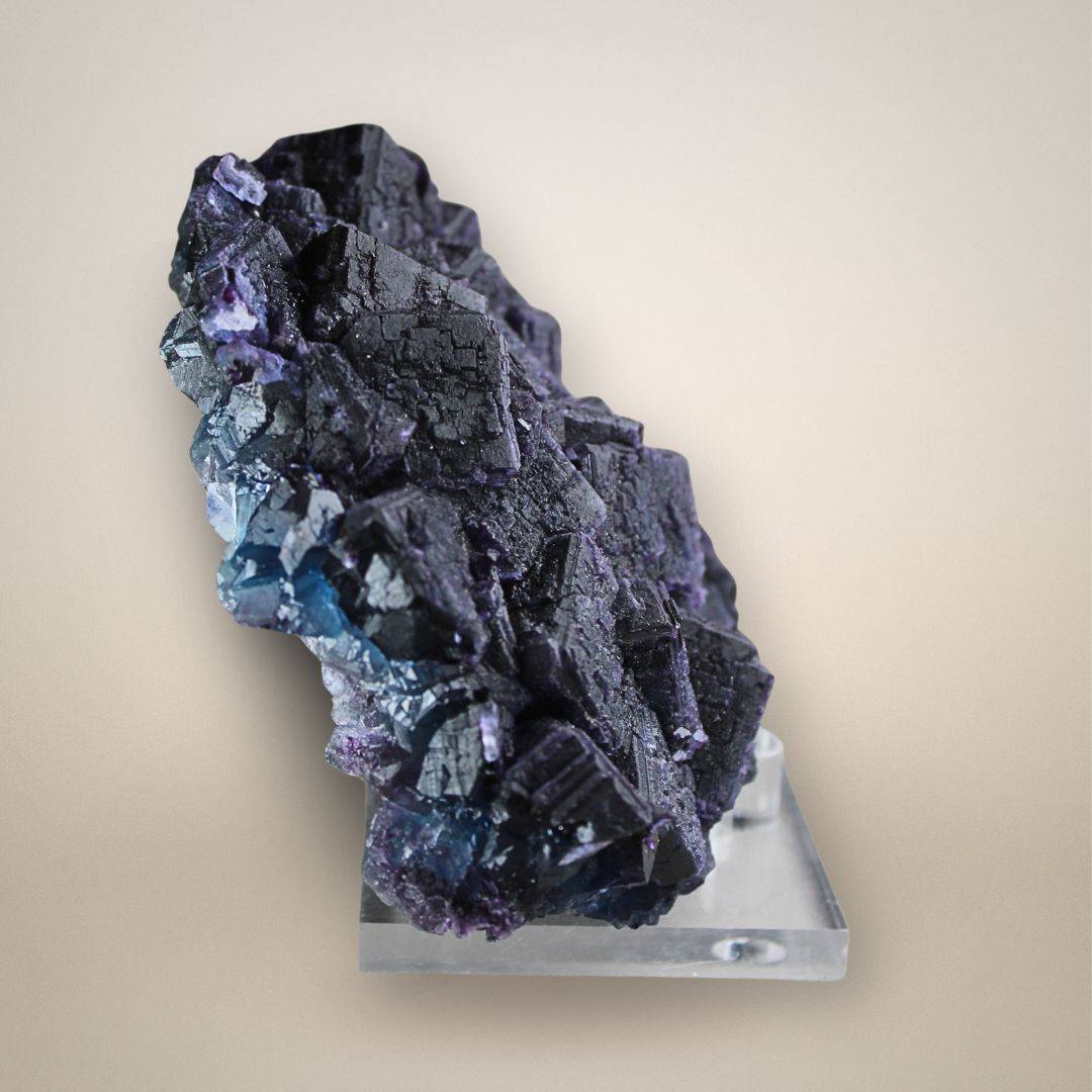 Side view of Chinese fluorite specimen revealing layered cubic growth, dark textured crystal faces, and translucent blue-violet edges.