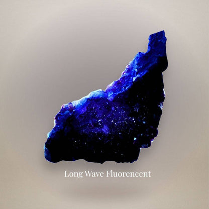 Chinese fluorite plate displaying intense blue-violet fluorescence concentrated along its upper edge and across portions of the crystal surface under long-wave UV light.