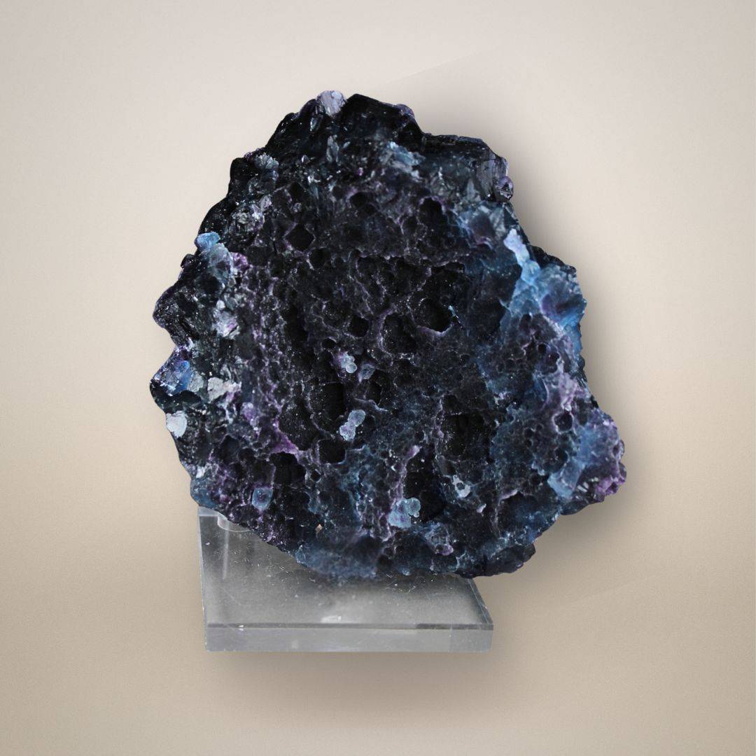 Back of fluorite cluster from China showing irregular pitted surfaces, small cavities, and areas of blue and purple coloration.